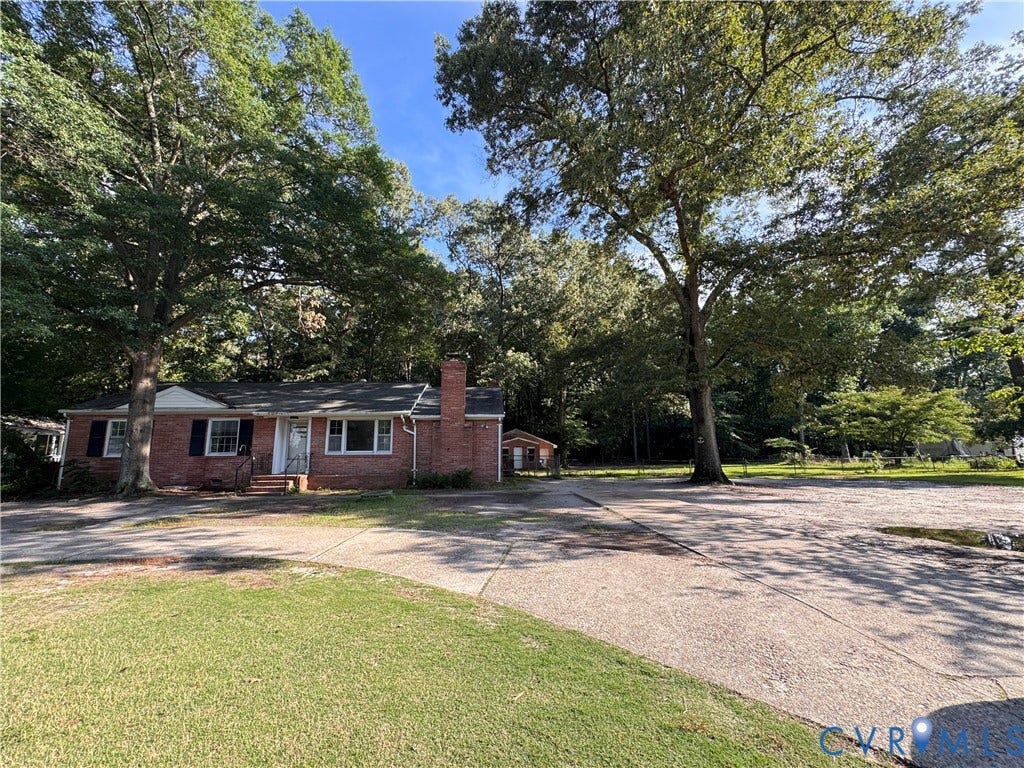 Traditional brick residence featuring a charcoal shingle roof and white trim