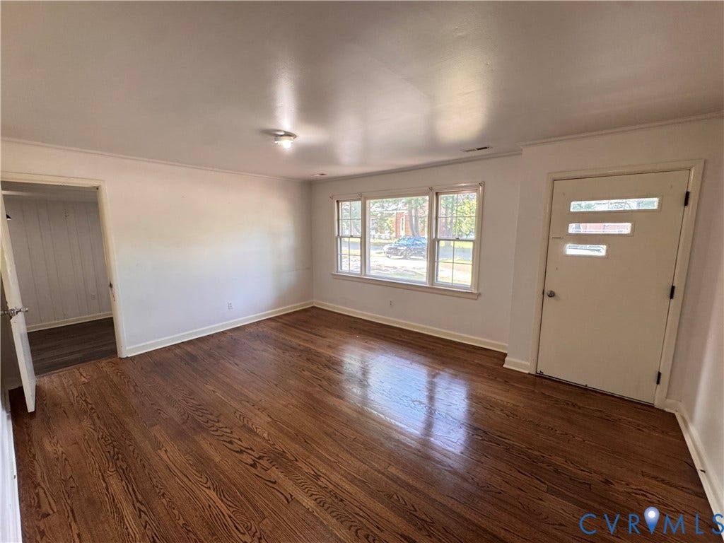 Hardwood flooring throughout, white walls, and a recessed window featuring multiple panes