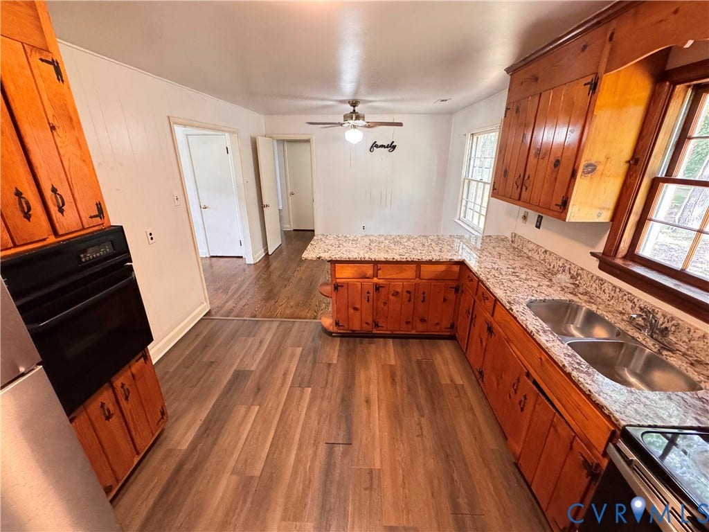 Kitchen featuring wood-finish flooring, wood cabinetry with decorative hardware, and granite-style countertops