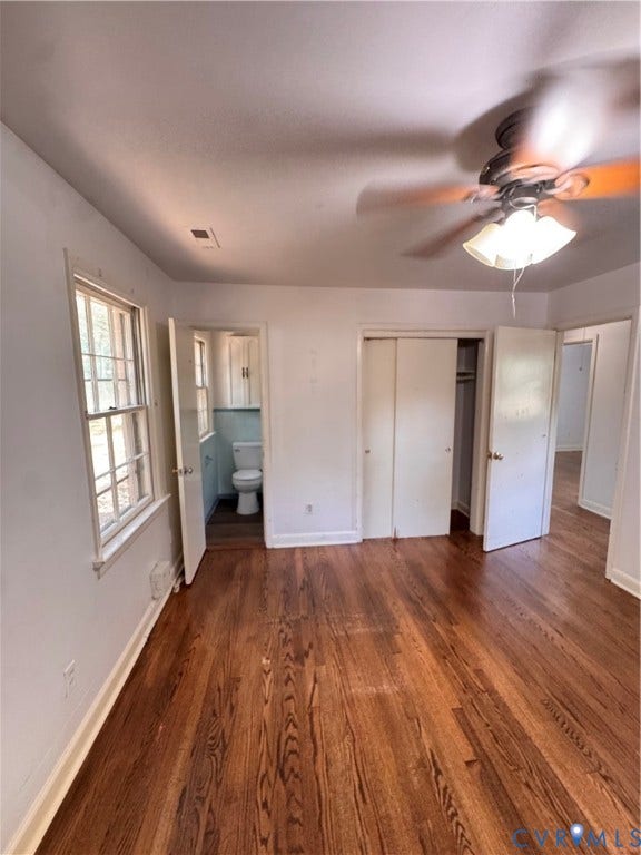 Hardwood flooring throughout, two windows, ceiling fan with light fixture, and a closet with bifold doors