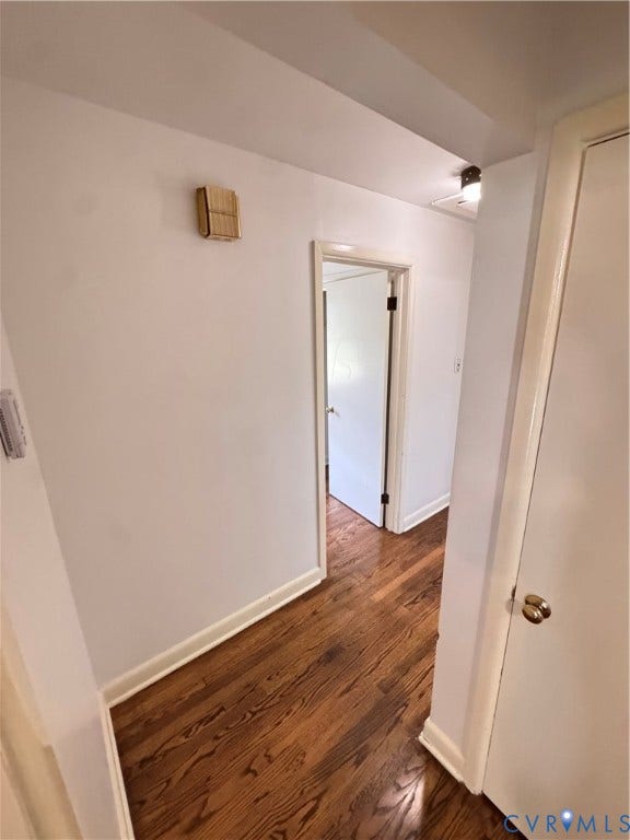 Hallway featuring wood-finish flooring, white painted walls, and white trim