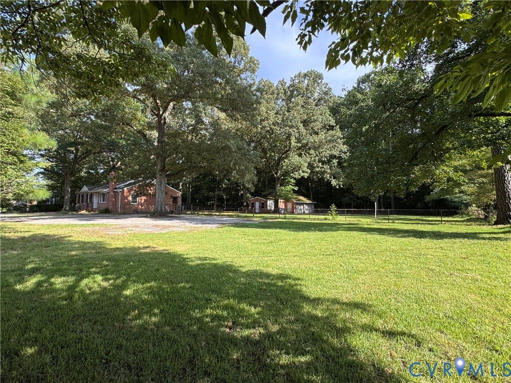 Expansive grassy lawn with mature trees and a brick-sided residence