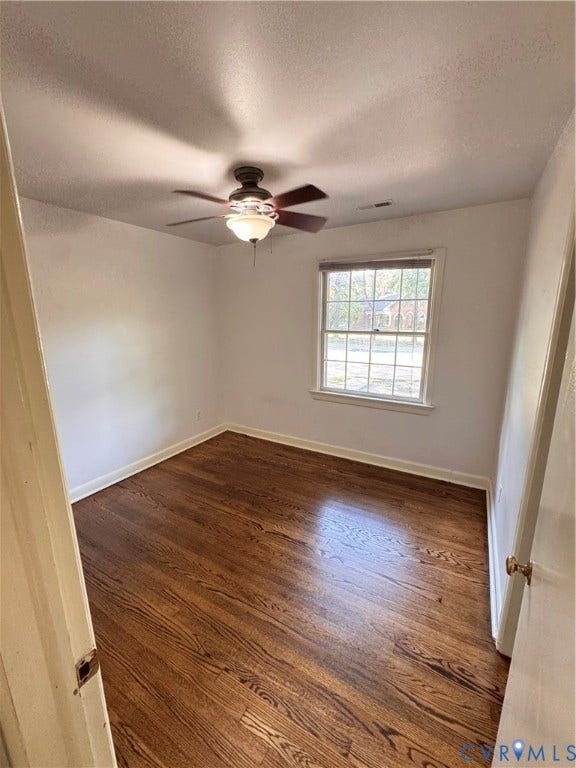Room with rich wood-finish flooring, white walls, and a ceiling fan with integrated lighting