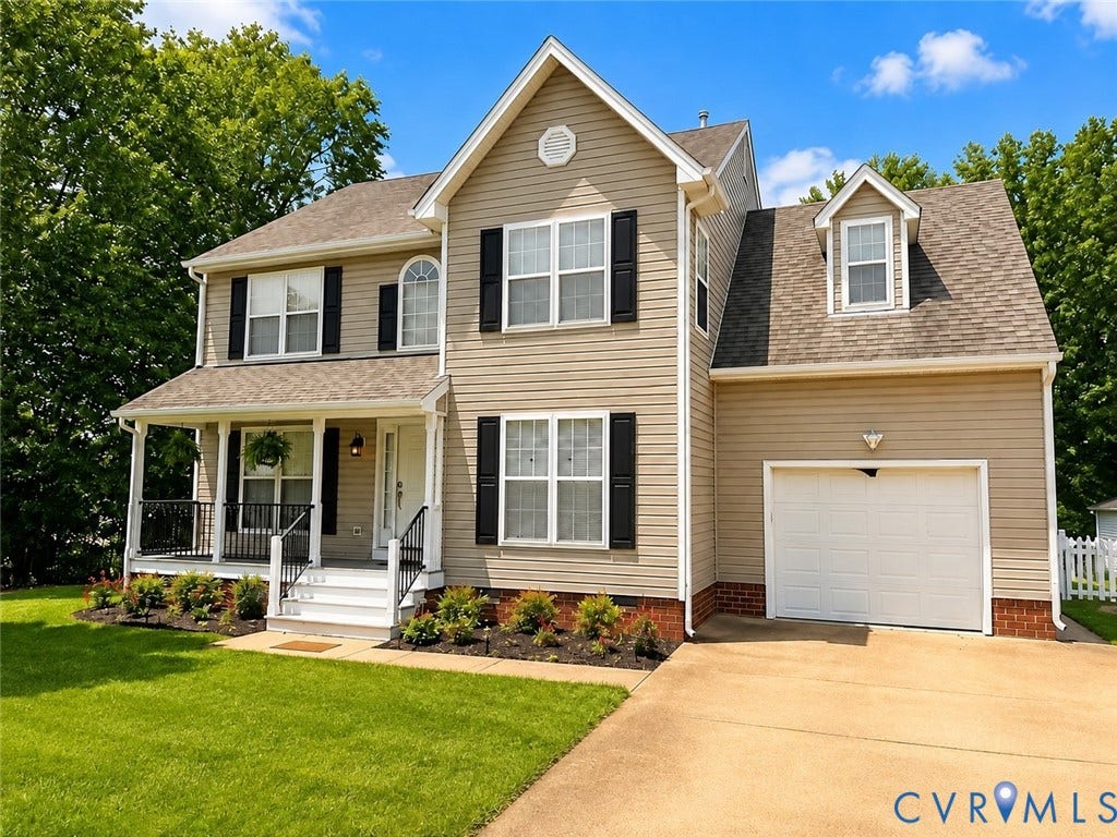 Two-story residence featuring siding exterior, a covered front porch with railing, attached garage, and a dormer window
