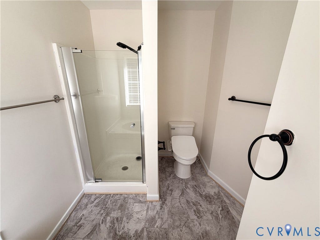 Walk-in shower with clear glass enclosure and white basin