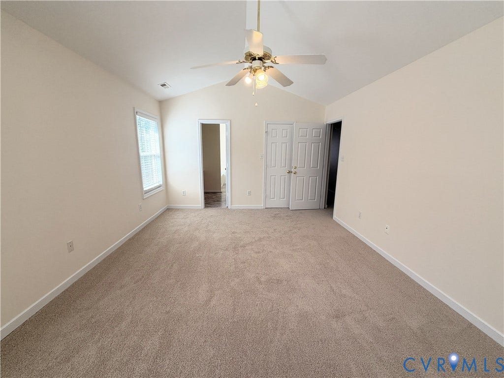Vaulted ceiling with a ceiling fan, neutral wall paint, carpet flooring, window with blinds, and white panel doors