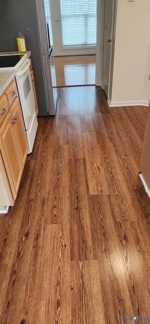 Wood-finish flooring throughout, with light wood cabinetry and a white built-in stove