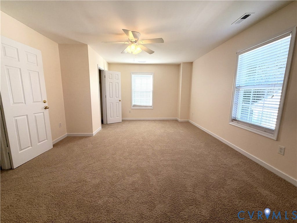 Carpeted flooring, ceiling fan, and multiple windows with blinds