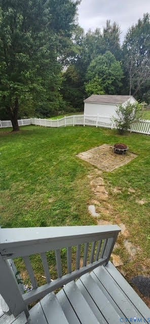 Rear yard with picket fencing, a storage shed, and a stone patio area