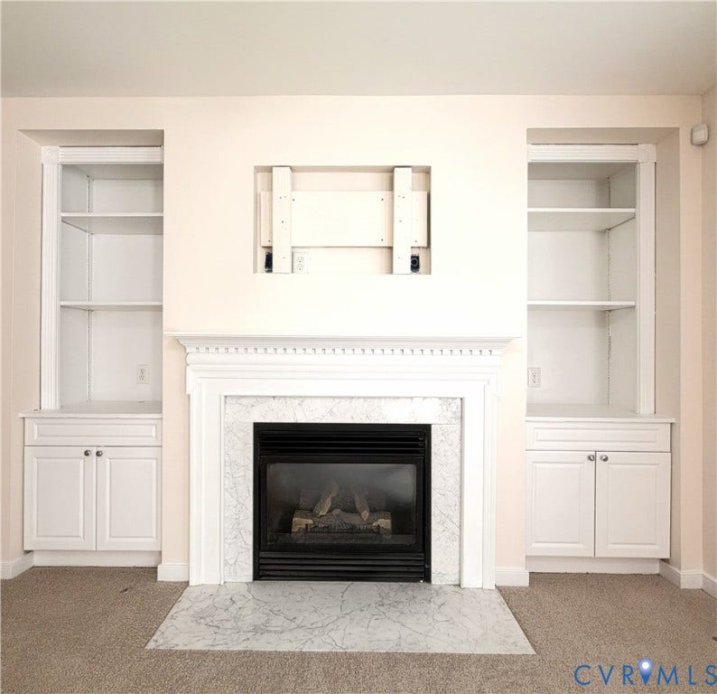Built-in fireplace with a stone surround and hearth, flanked by built-in shelving and lower cabinetry