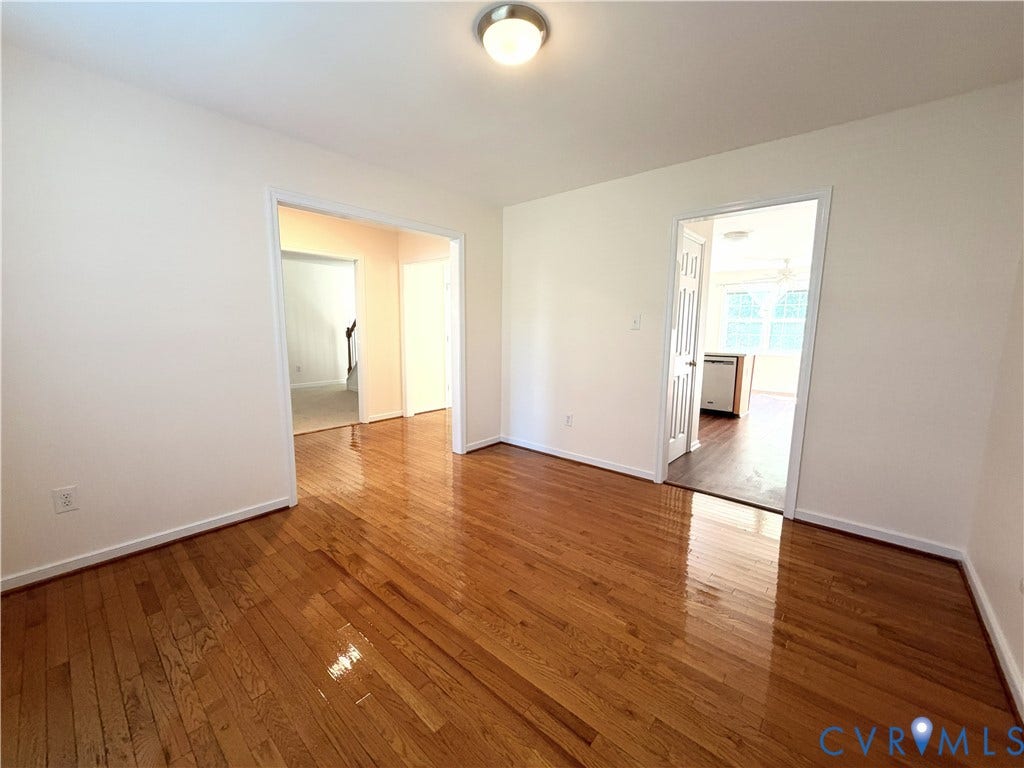 Hardwood flooring throughout, white painted walls, and ceiling-mounted lighting