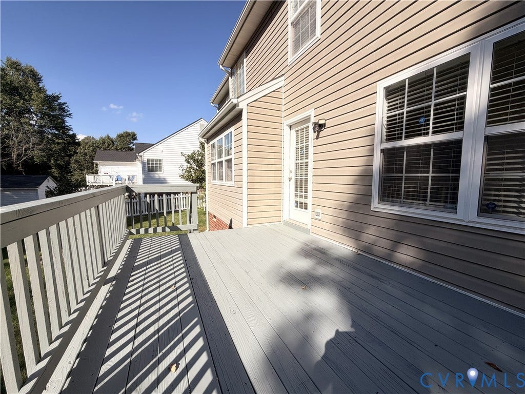 Expansive exterior deck with painted wood railing, direct access to the interior, and tan horizontal siding