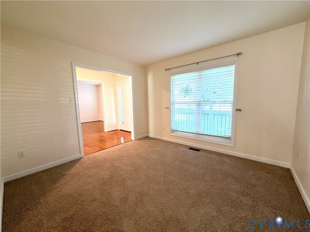 Spacious carpeted bedroom with abundant natural light from a sliding glass door and additional window