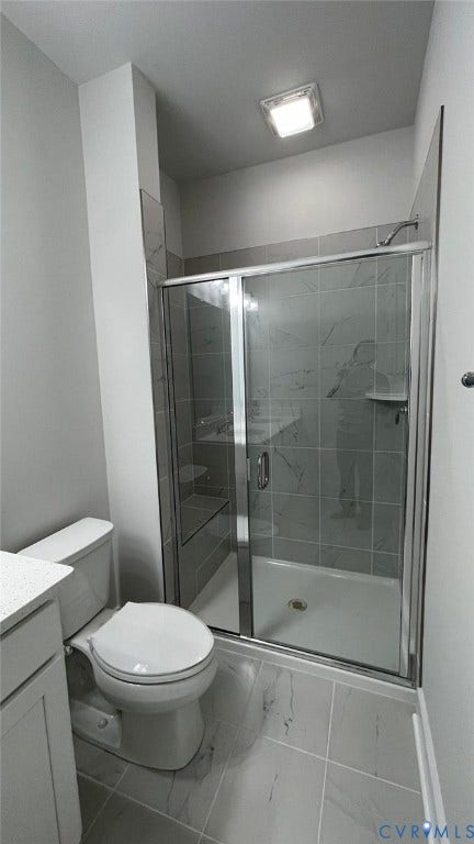 Bathroom featuring vanity, toilet, and a shower with shower door