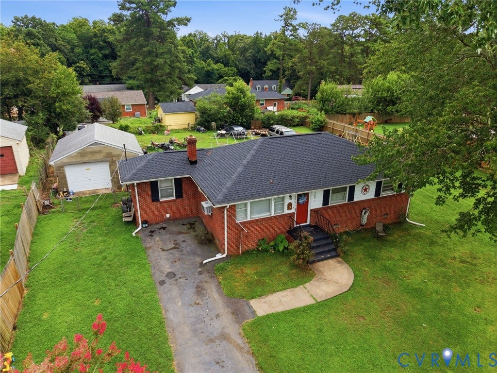 Brick ranch-style home featuring a dark shingle roof, white trim, and an attached red front door
