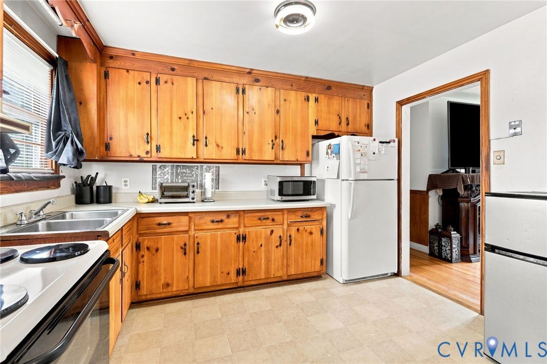 Kitchen featuring wood cabinetry, laminate countertops, a double basin stainless steel sink, and light-colored flooring