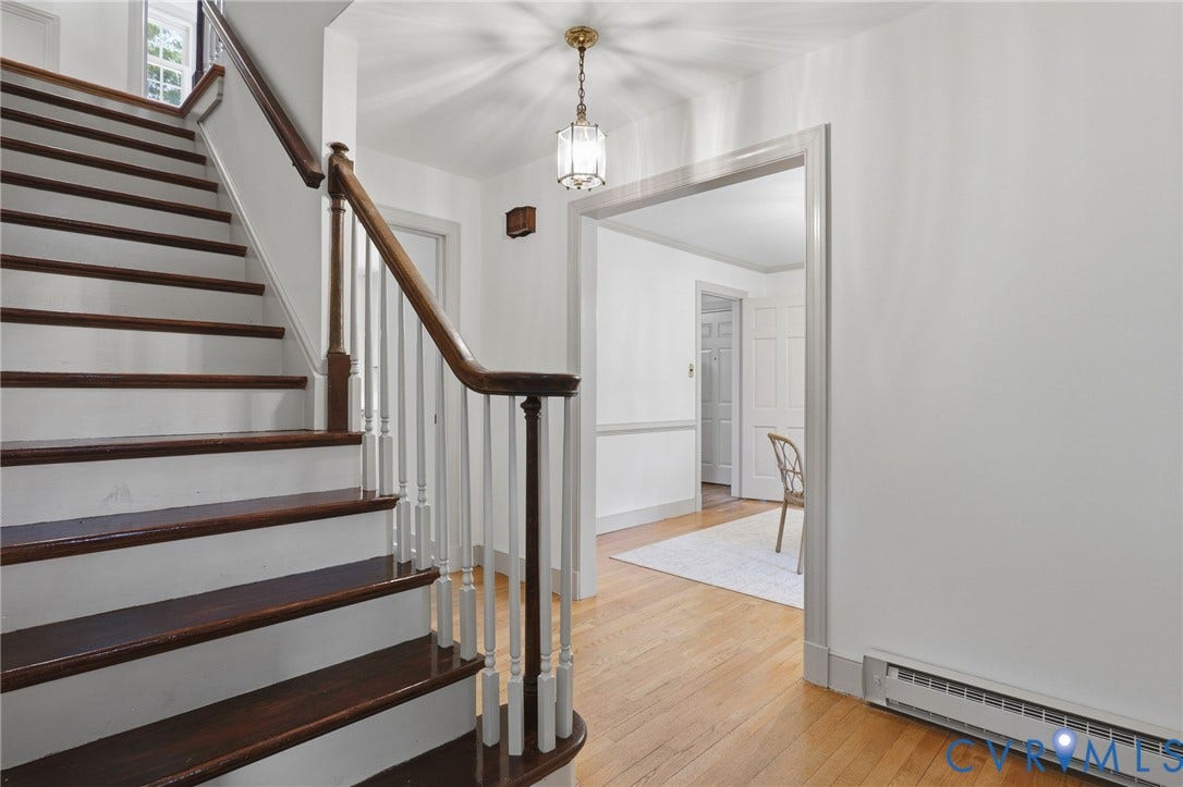 Entryway featuring a wood staircase with white risers and balusters, a wood handrail, and light wood-finish flooring