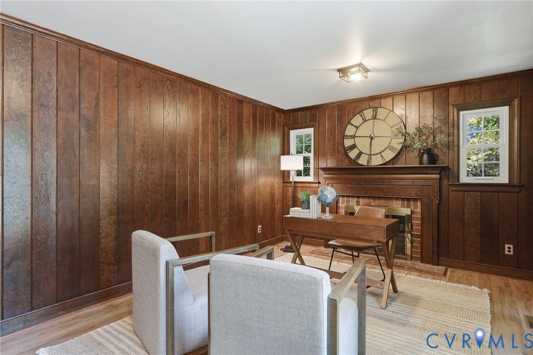 Room featuring extensive wood-paneled walls, a brick fireplace with a wood mantel, and wood-finish flooring