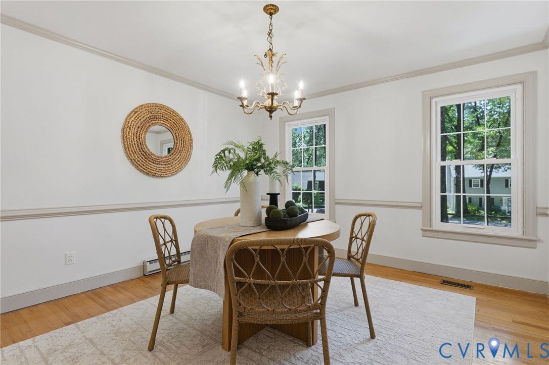 Dining area featuring hardwood flooring, crown molding, double-hung windows, and an overhead chandelier