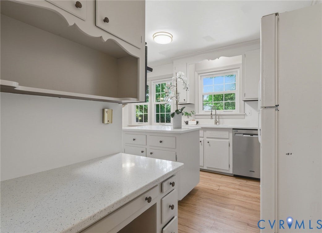 Kitchen featuring white cabinetry, light-toned countertops, wood-finish flooring, and a stainless steel dishwasher