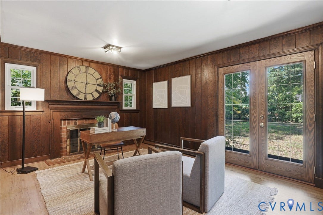 Wood-paneled room featuring a brick fireplace with a wood mantel, two casement windows, wood-finish flooring, and double glass doors opening to the outdoors