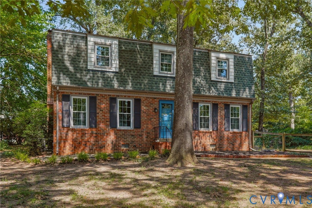 Brick and siding exterior featuring a gambrel roofline with dormer windows