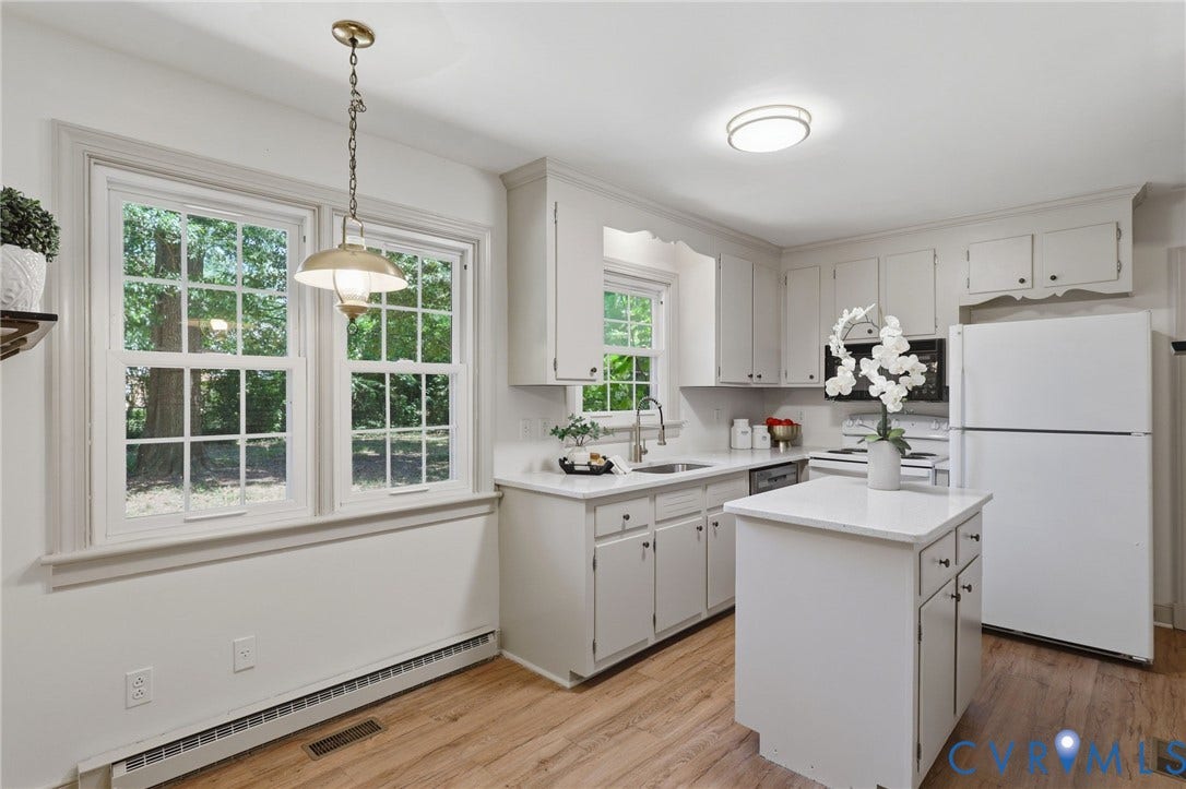 Kitchen featuring light-finish cabinetry, a central island with storage, wood-finish flooring, and white countertops