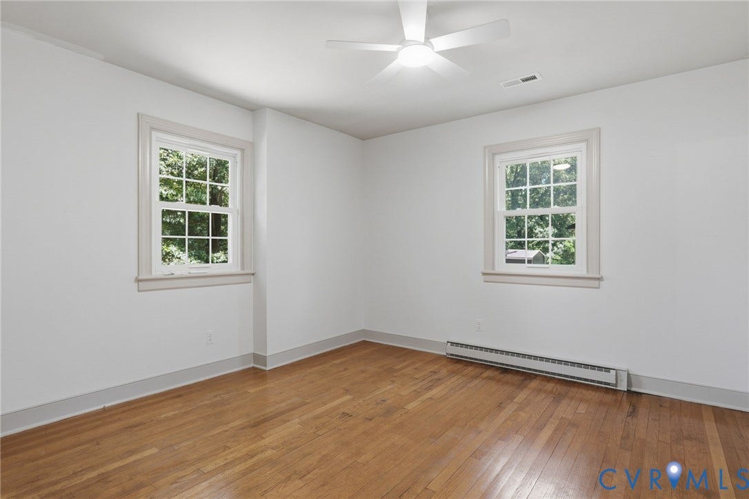 Room featuring light wood-finish flooring, white walls, and two multi-pane windows with trim