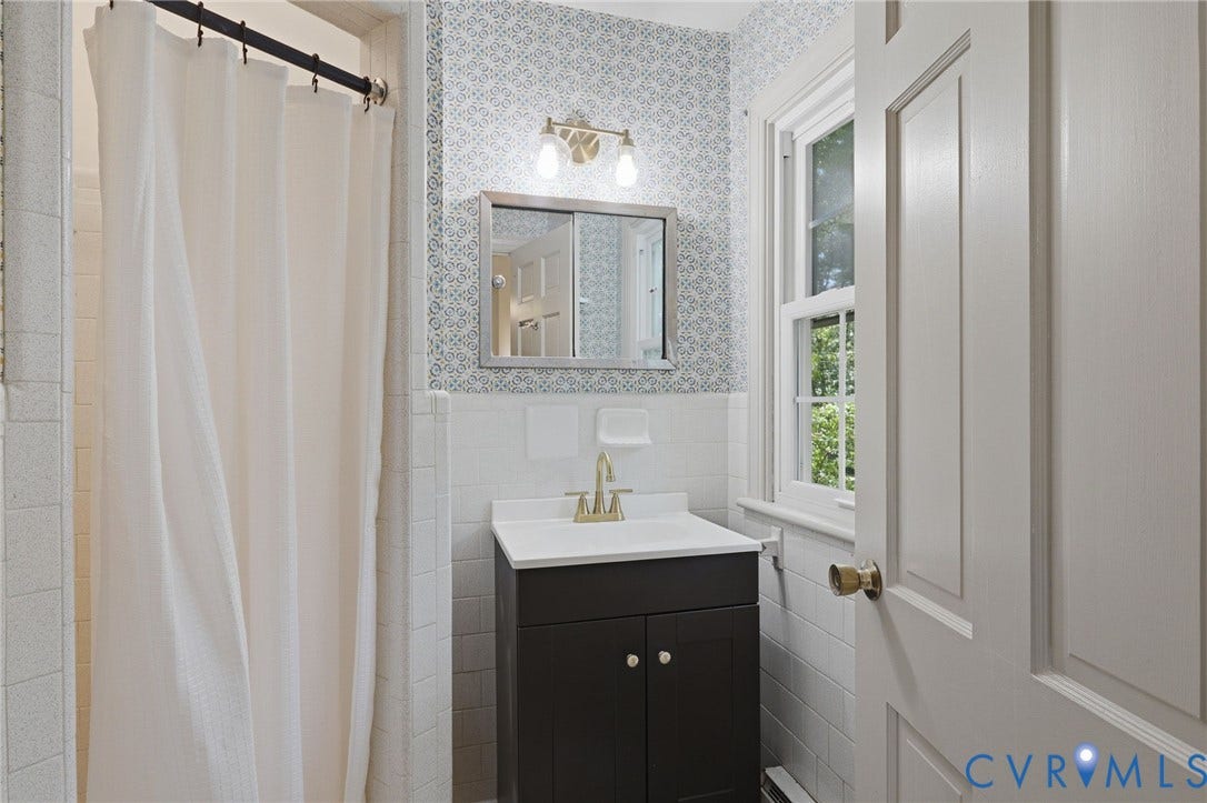 Bathroom with a dark wood-finish vanity, white countertop, and gold-tone faucet