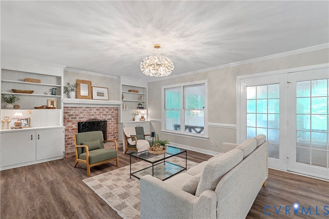 Living area featuring wood-finish flooring, a brick fireplace with a white mantel, and built-in shelving and cabinetry