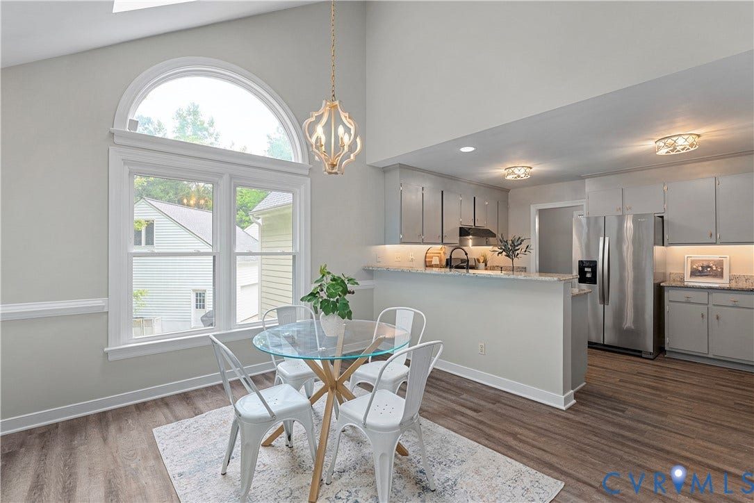 Dining area featuring a soaring vaulted ceiling, an arched window, wood-finish flooring, and a decorative chandelier