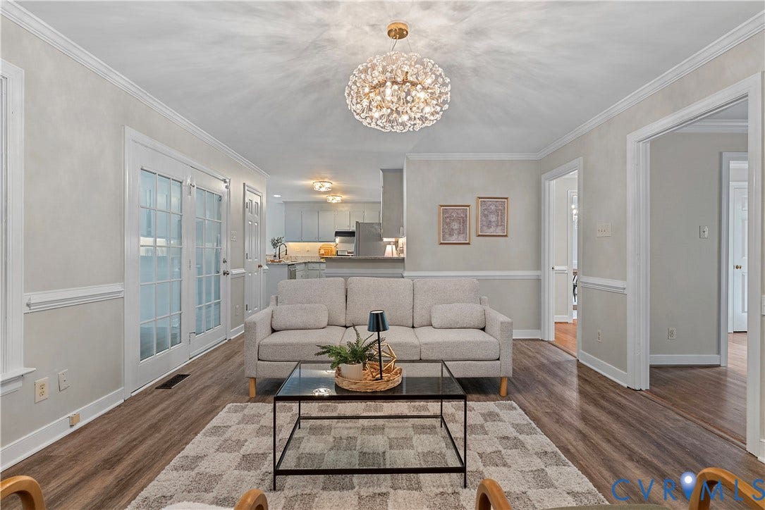 Spacious living area featuring wood-finish flooring, a contemporary crystal chandelier, and white trim molding