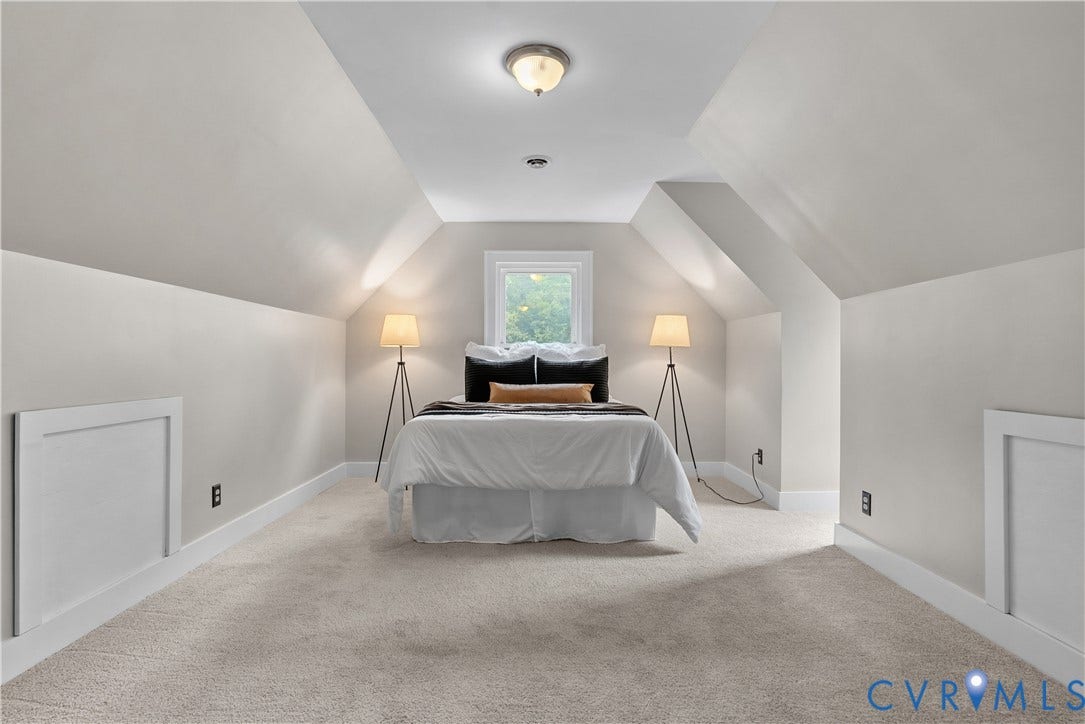 Carpeted room featuring a white window, sloped ceilings, and built-in access panels