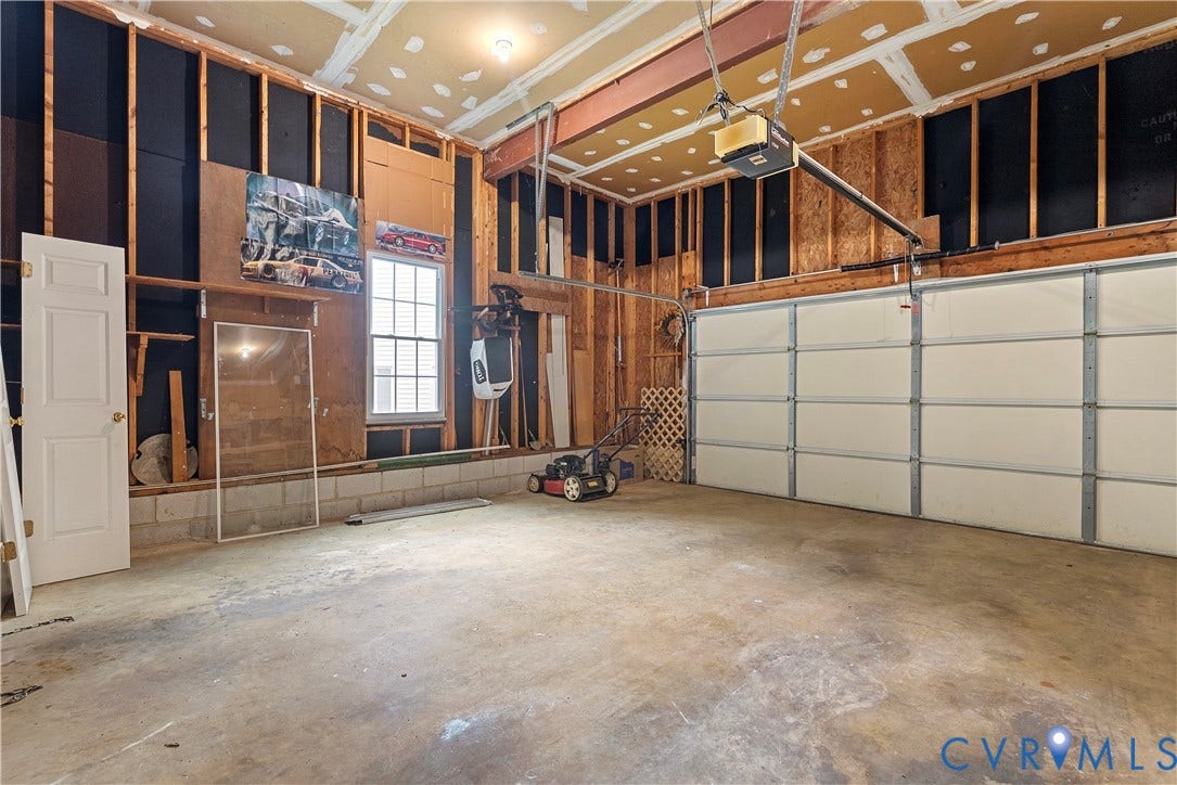 Two-car garage featuring a concrete floor, exposed wood framing, and two panel garage doors with an automatic opener
