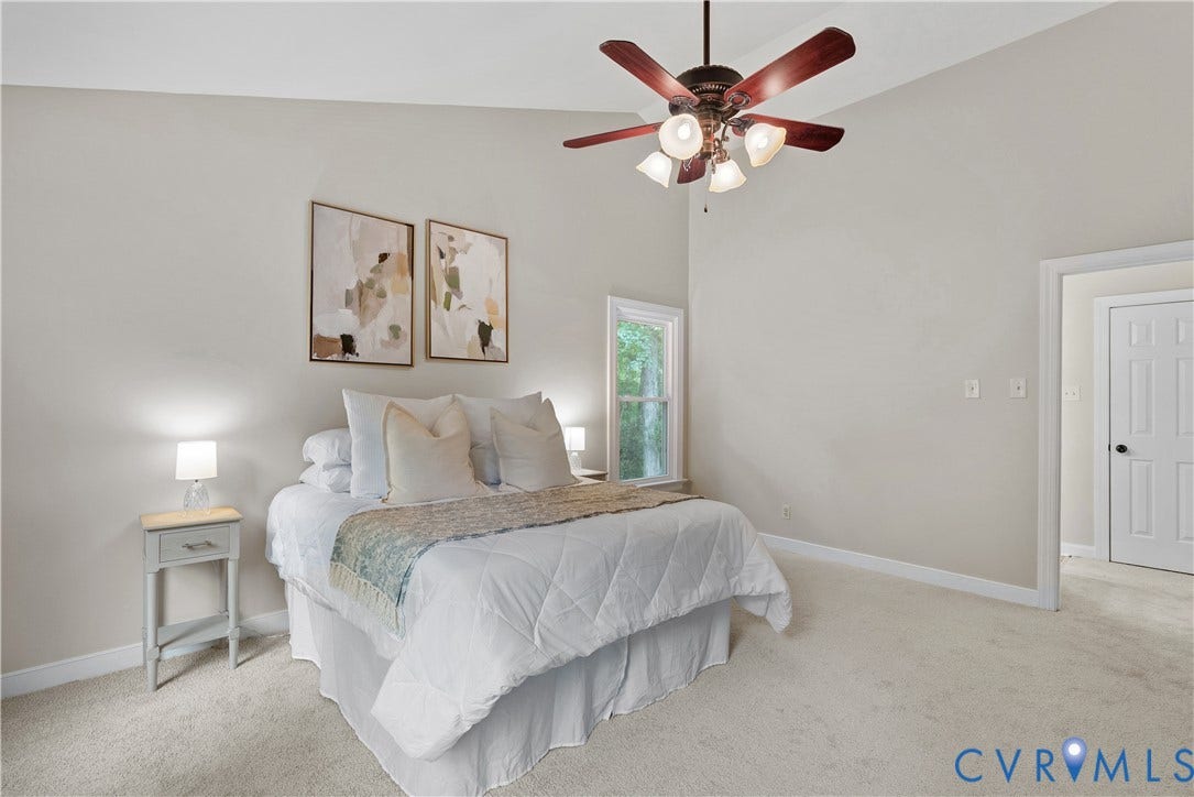 Spacious bedroom showcasing neutral wall finishes, plush carpeting throughout, and abundant natural light from multiple windows
