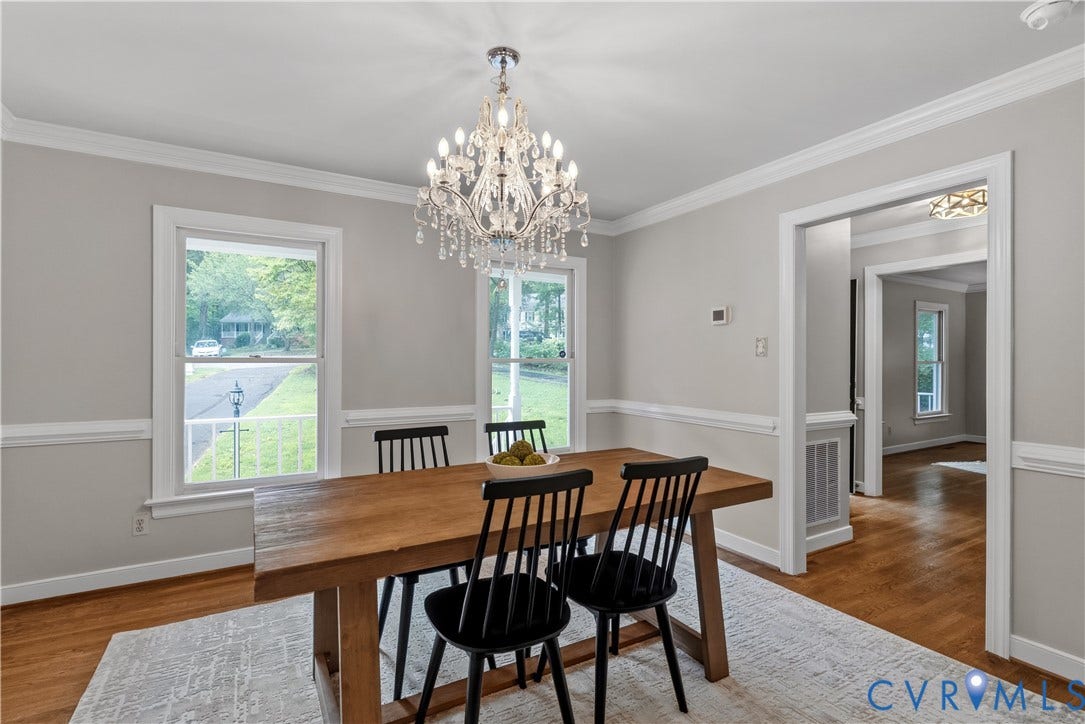 Dining space featuring a crystal chandelier, wood-finish flooring, and white trim molding