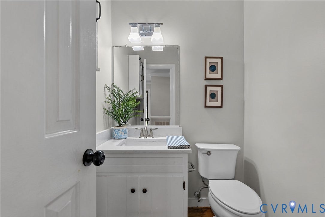 White vanity with cabinet storage, a single basin sink, and a countertop