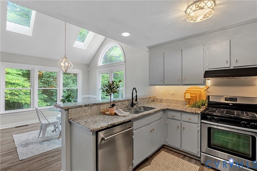 Bright, light-filled kitchen featuring custom cabinetry with ample storage, granite countertops, and a center island with undermount sink