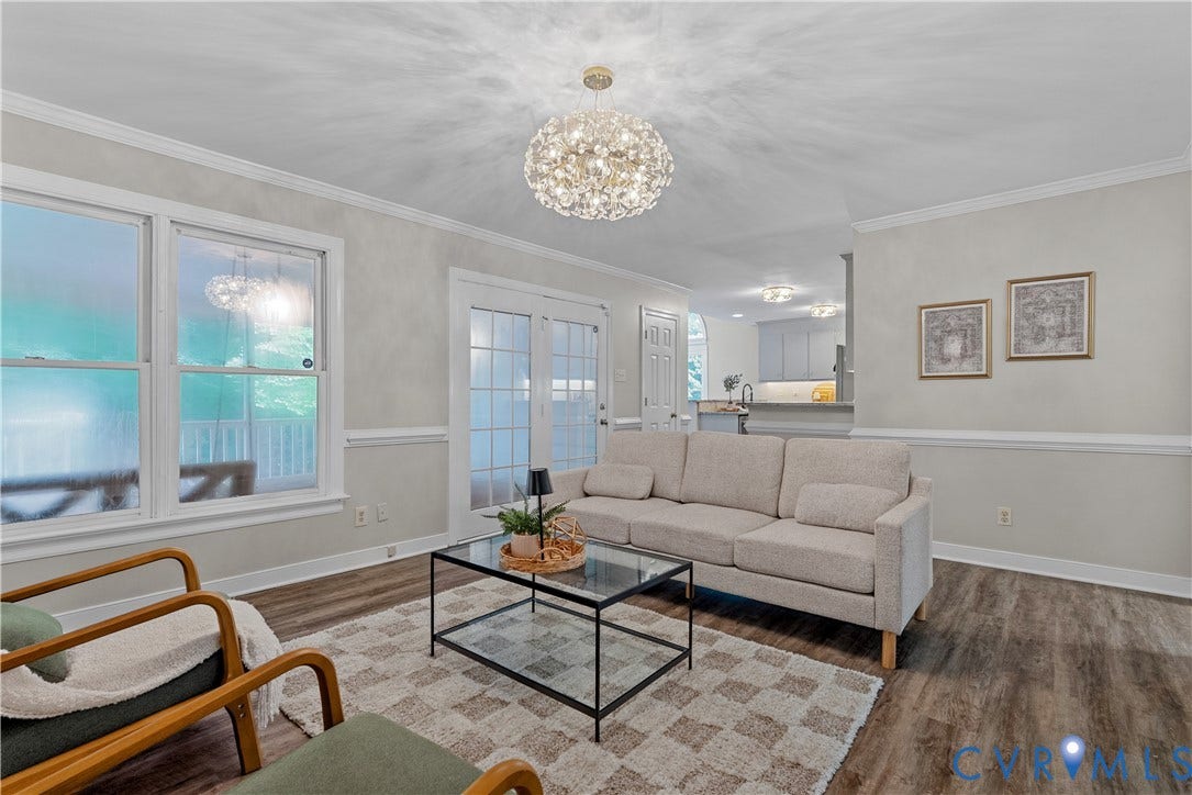 Living area featuring wood-finish flooring, white crown molding, and two large windows