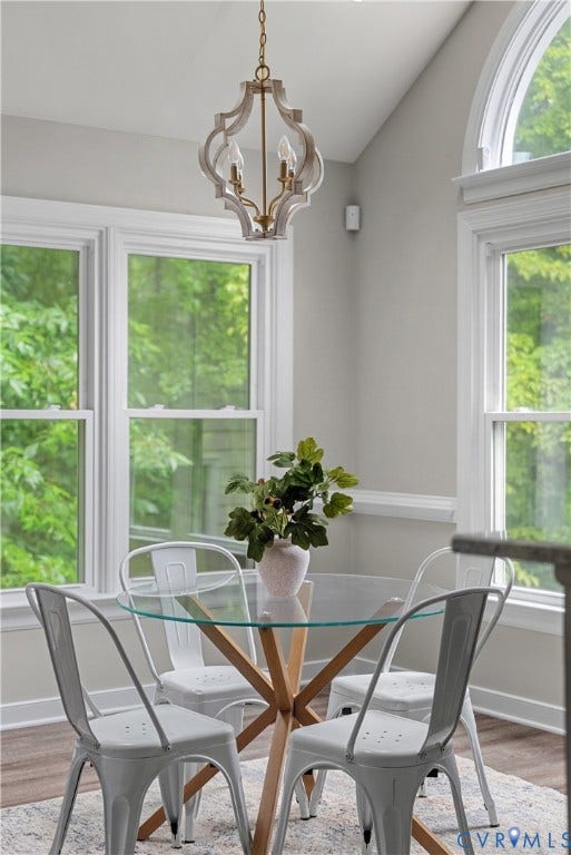 Vaulted ceiling with an ornate chandelier, multiple windows, and light wood-finish flooring
