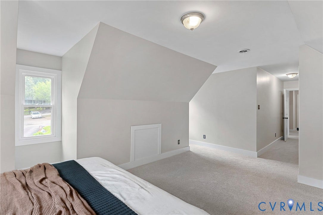 Attic room featuring a single window, sloped ceilings, light gray wall paint, white trim, and light-colored carpeting