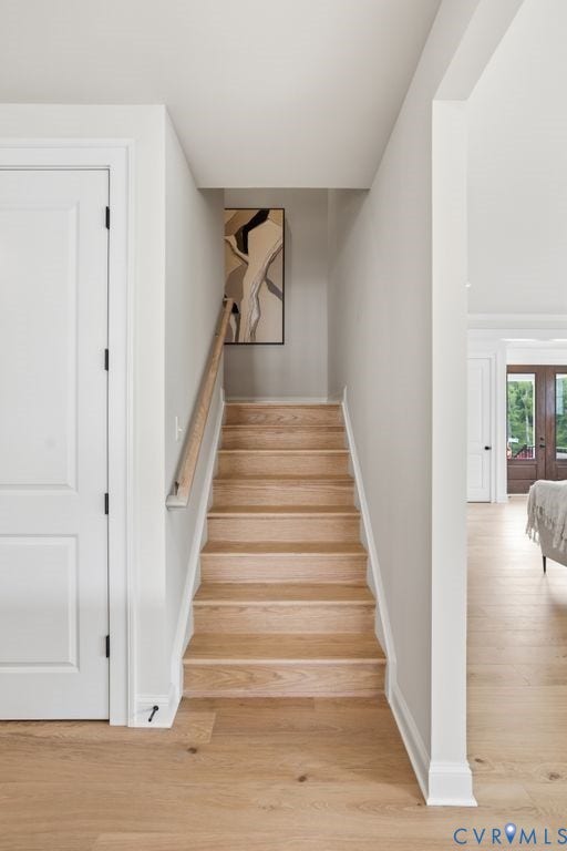 Hardwood staircase with natural wood steps and handrail, complemented by light wood-finish flooring