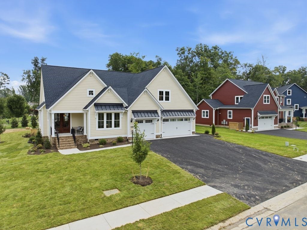 Cream-colored siding home featuring a dark shingle roof, stone foundation accents, and a covered front porch