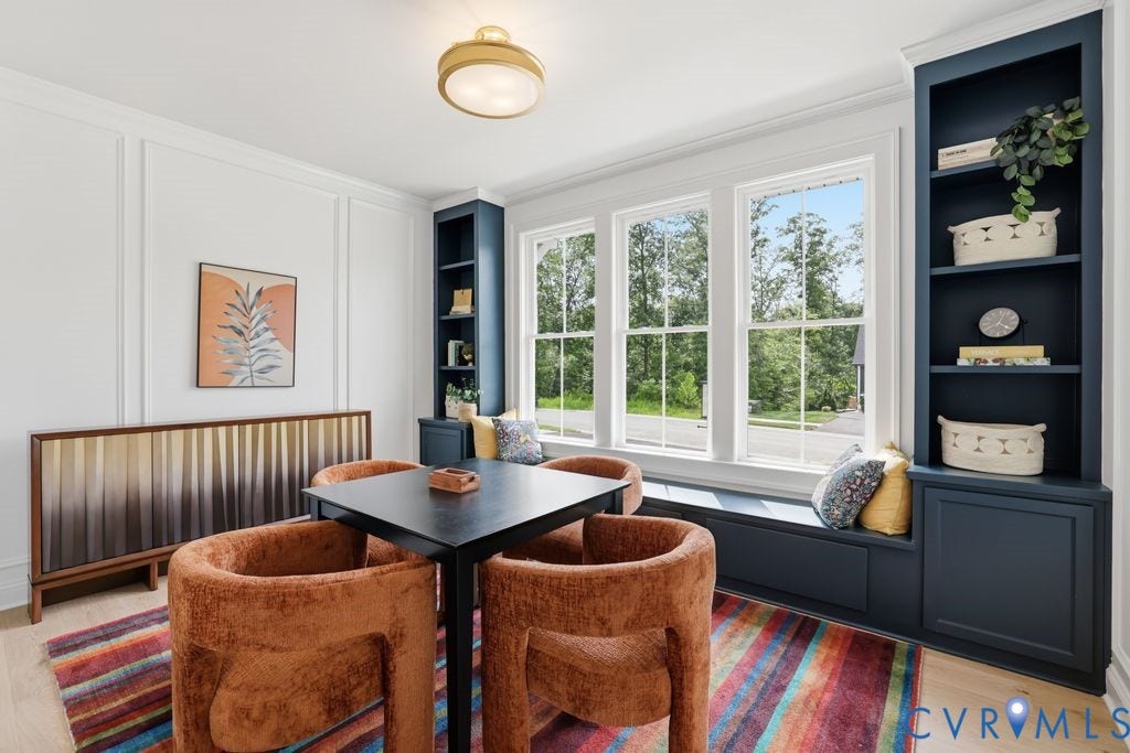 Room featuring three large windows, a built-in window seat, and built-in shelving units