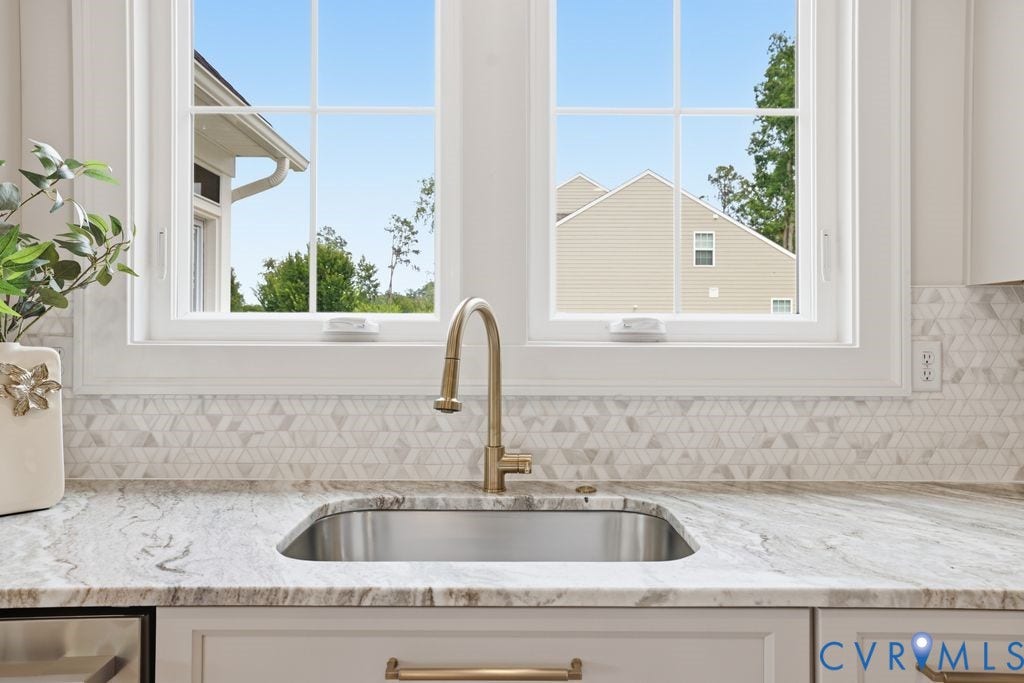 Kitchen sink with a gold-finish faucet, under-mount stainless steel sink, and light-toned countertop