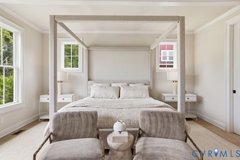 Bright bedroom featuring light-toned walls and wood-finish flooring