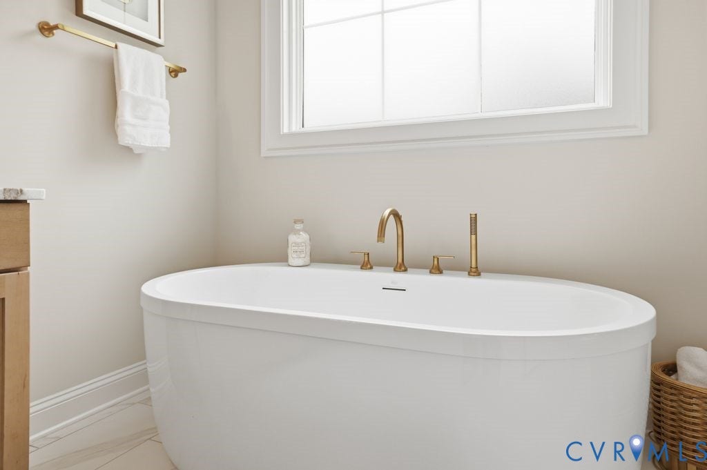 Freestanding oval bathtub featuring brass fixtures and a built-in handheld shower