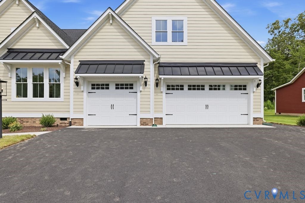 Two-car garage with white paneled doors, black decorative hardware, and upper window lites