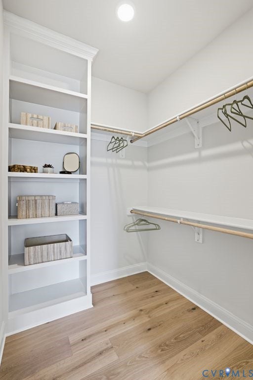 Built-in shelving, two levels of hanging rods, and wood-finish flooring define this bright closet space
