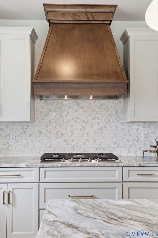 Custom wood range hood with integrated lighting, set above a mosaic tile backsplash and a gas cooktop